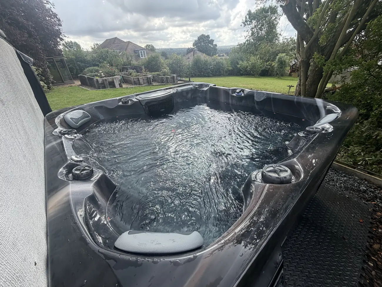 Newly installed hot tub filled and running in a garden with countryside views