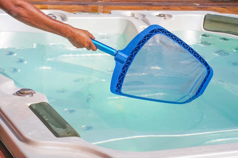 Skimming crystal-clear hot tub water during a service